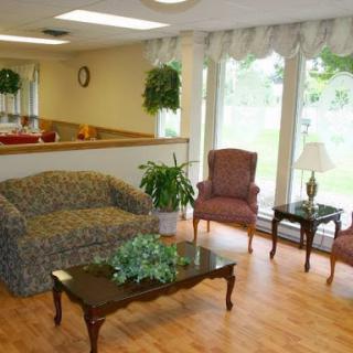 A cozy and inviting living room area featuring a patterned sofa, comfortable chairs, and a coffee table surrounded by greenery.