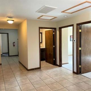 A simple hallway with tile flooring and multiple wooden doors.