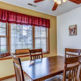 A cozy dining room with a wooden table and chairs near a large window adorned with red curtains.