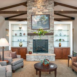 A cozy living room featuring a stone fireplace, comfortable seating, and elegant decor.