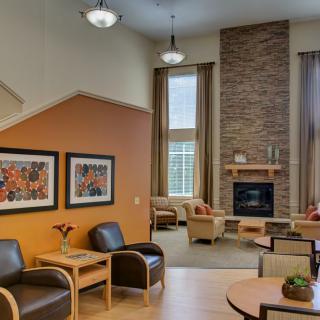 A modern living room with a cozy seating area, featuring a fireplace and decorative artwork on the walls.