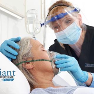 A nurse attends to a patient using an oxygen mask in a hospital setting.