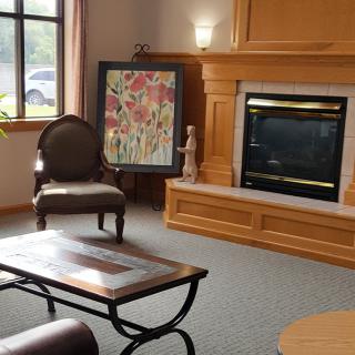 A cozy living room with a fireplace, artwork, and comfortable seating.