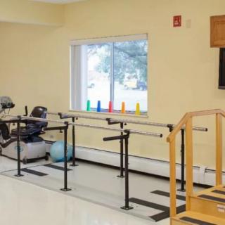 A therapy room equipped with parallel bars and exercise equipment for rehabilitation.