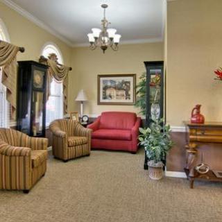 A cozy living room featuring a red sofa, striped armchairs, and elegant decor.