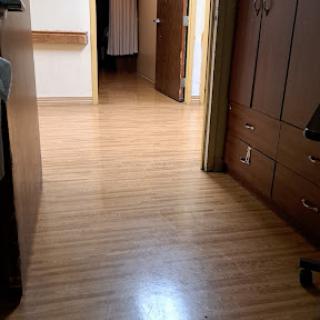 A view of a hallway with wooden flooring and open doors leading to different rooms.