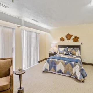 A cozy bedroom with a neatly made bed, a reading lamp, and stylish decor.