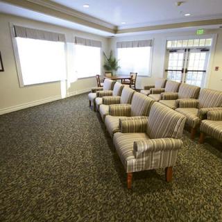 An empty waiting room with rows of cushioned chairs and large windows.