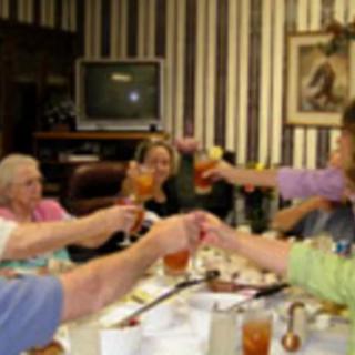 A group of people raising their glasses in a celebratory toast around a dining table.