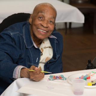 An elderly individual joyfully engaging in a painting activity.