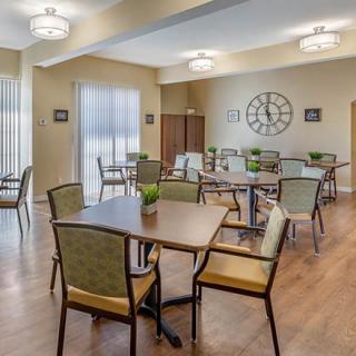 A cozy dining area with neatly arranged tables and chairs, featuring soft lighting and a warm ambiance.