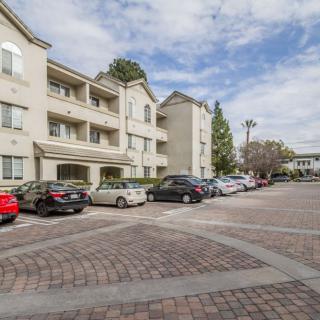 A view of an apartment complex with a parking lot filled with cars under a cloudy sky.