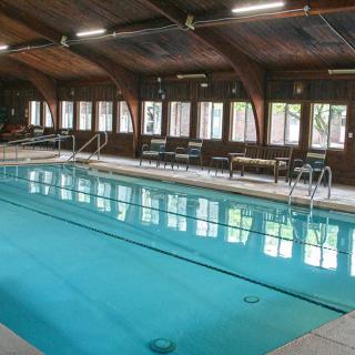 An indoor swimming pool with large windows and wooden roof beams.