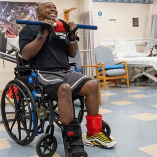 A person in a wheelchair performing upper body exercises with weights, focused on rehabilitation and physical therapy.