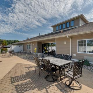 A spacious outdoor patio area with a dining table and chairs in a sunny backyard.