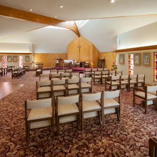 A peaceful interior view of a church, showcasing rows of empty chairs and wooden architectural elements.
