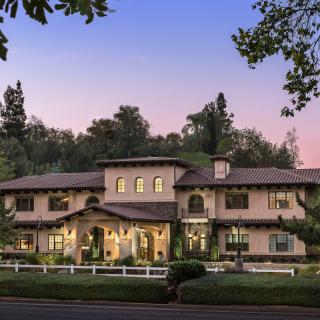 A luxurious mansion surrounded by trees during the evening.