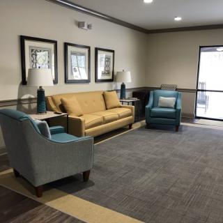 A cozy living room with beige and blue furniture, including a sofa and armchairs, complemented by lamps and framed artwork on the walls.