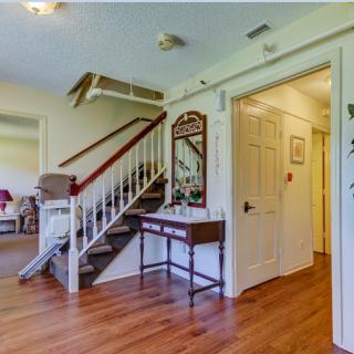 A cozy home interior featuring a staircase, wooden flooring, and a decorative mirror above a small table.