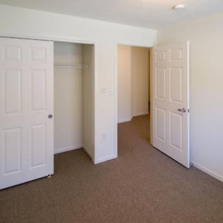 A view of an empty room featuring two closet doors and a doorway leading to another area.