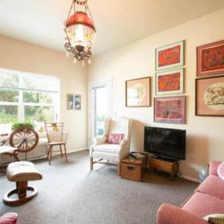 A cozy living room with eclectic decor, featuring a comfortable seating area, a television, and various artworks on the walls.