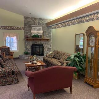 A cozy living room with a stone fireplace, comfortable seating, and a grandfather clock.
