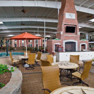 A spacious indoor recreation area featuring a pool and dining space, complete with a fireplace and lounge chairs.