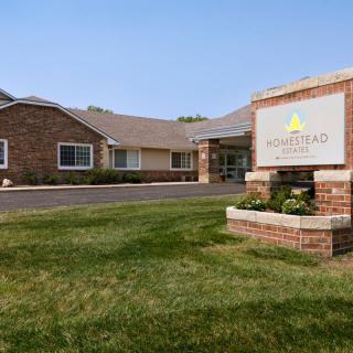 A brick building with a sign and well-maintained grass in the foreground.