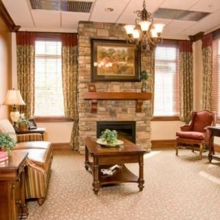 A cozy living room with traditional decor, featuring a stone fireplace and elegant furnishings.