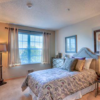 A cozy bedroom with a large window, patterned bedding, and stylish decor.