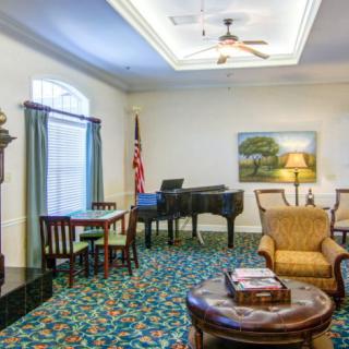 A spacious living room featuring a grand piano, comfortable seating, and elegant decor.