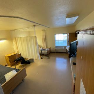 A spacious and well-lit room featuring a bed, furniture, and a window with natural light.