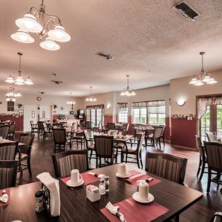 A spacious restaurant dining area with neatly arranged tables and chairs, soft lighting, and a warm atmosphere.
