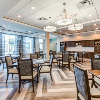 A modern dining area with neatly arranged tables and chairs, featuring stylish lighting and wood flooring.