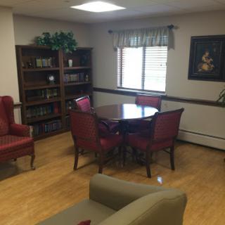 A cozy indoor space featuring a table and chairs, complemented by bookshelves and natural light.