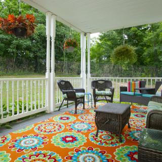 A cozy porch with colorful decor and comfortable seating.