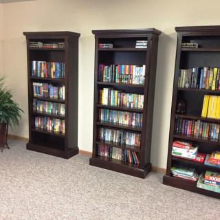 A cozy library space featuring three tall bookshelves filled with a variety of books.