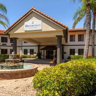 A sunny view of a building entrance with a fountain and palm trees.