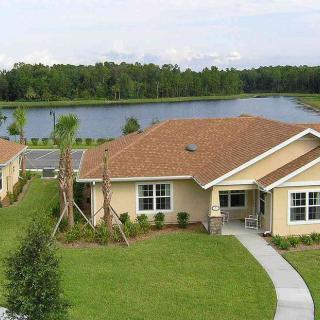 A suburban house with a well-maintained lawn overlooking a serene lake.