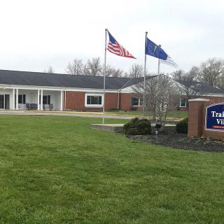 A brick building with flags and a sign on a well-maintained lawn.