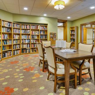 A cozy library room with bookshelves, a table, and chairs for reading.