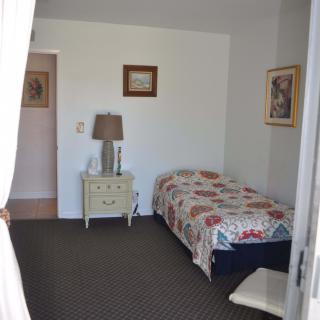 A cozy bedroom with a single bed, side table, and decorative artwork.