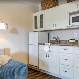 A cozy kitchenette with white cabinets, a small fridge, and a microwave.