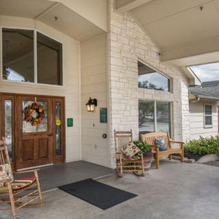 A welcoming building entrance with rocking chairs and seasonal decorations.