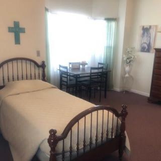 A cozy bedroom with a single bed, table and chairs, and simple decor.