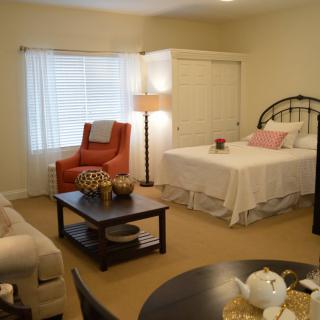 A cozy bedroom interior with a bed, armchair, lamp, and coffee table.