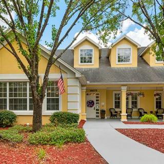 A charming yellow house with a welcoming porch and landscaped front yard.