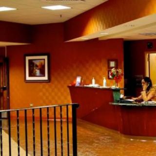 A warmly-lit reception area in a hotel with a staff member at the desk.