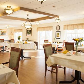 An empty dining room with neatly arranged tables and chairs, featuring elegant decor and soft lighting.
