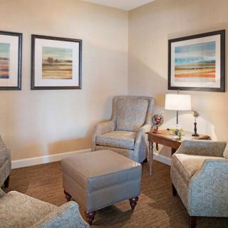 A cozy living room with armchairs, an ottoman, and wall art.